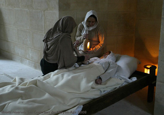 Hospitaalzusters verzorgen een zieke vrouw in hun gasthuis. Reconstructie door Les guerriers du Moyen-Age