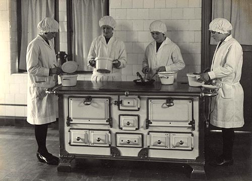 4 leerlingen rond het kookfornuis in de keukenklas (1938)