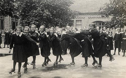 rolschaatsters maken dolle pret op de speelplaats (juli 1938)